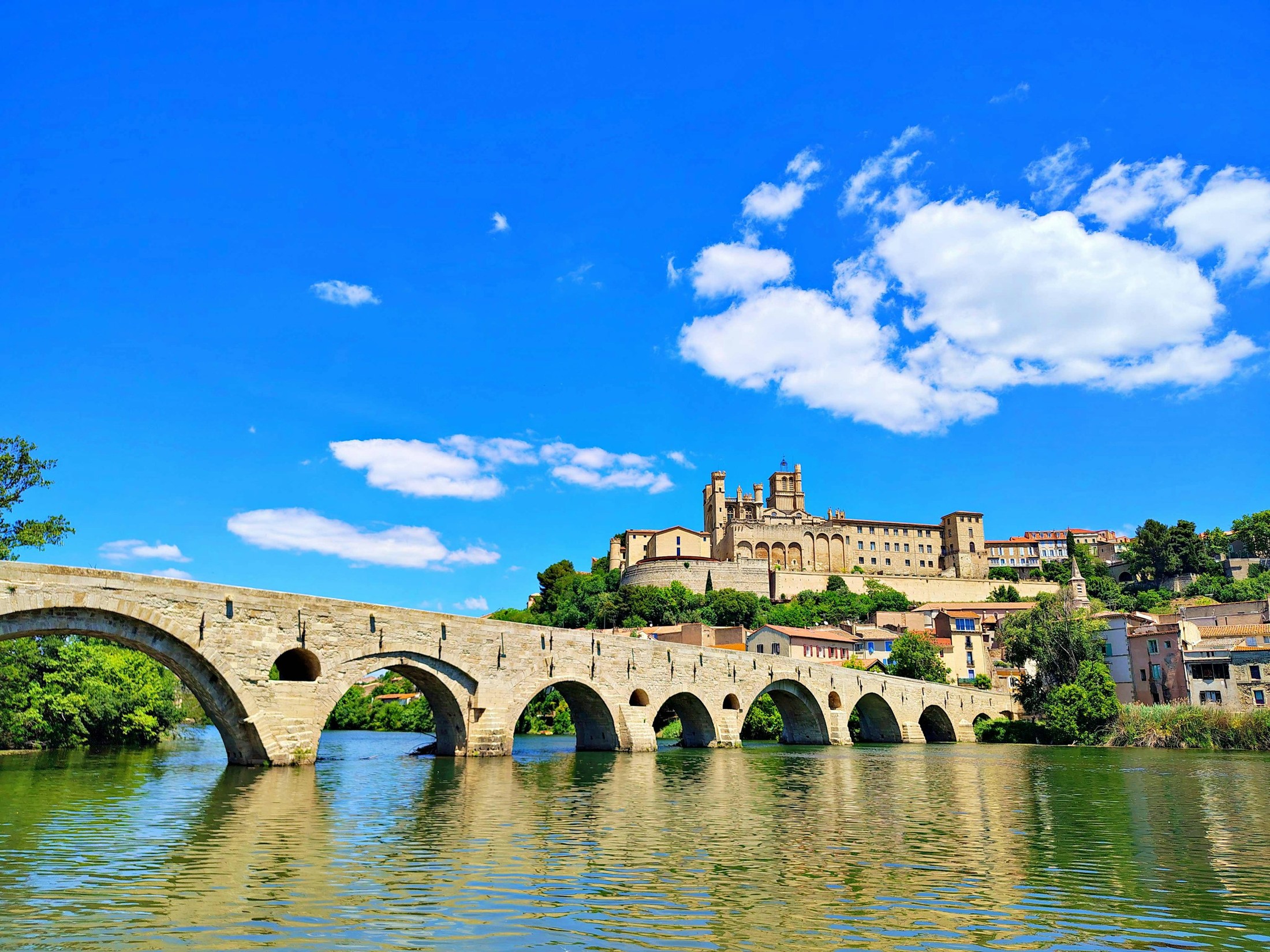 The Pont Vieux over the River Orb in Béziers, France, with the Béziers Cathedral in the background. | Béziers in France