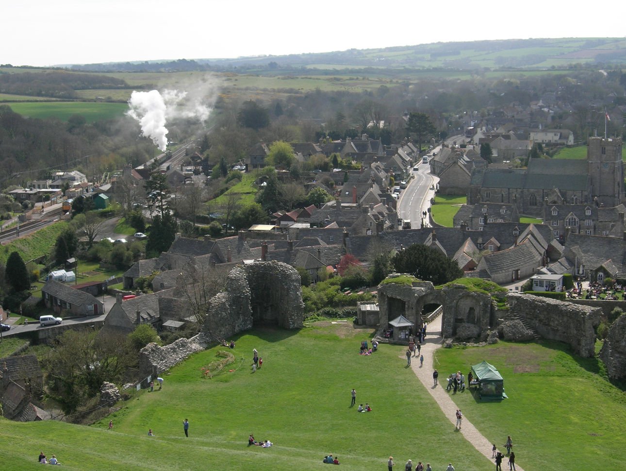 Corfe Castle village, as seen from Corfe Castle itself. The station is on the left, with steam engine in the distance. | Corfe Castle in United Kingdom