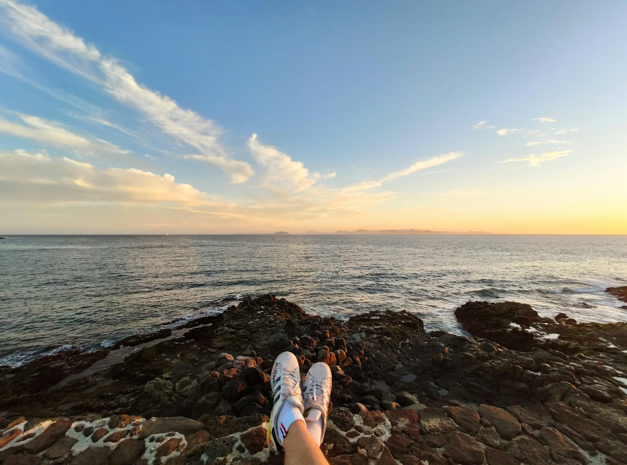 enjoying sitting at the seaside wearing adidas sneakers | Playa Blanca in Spain