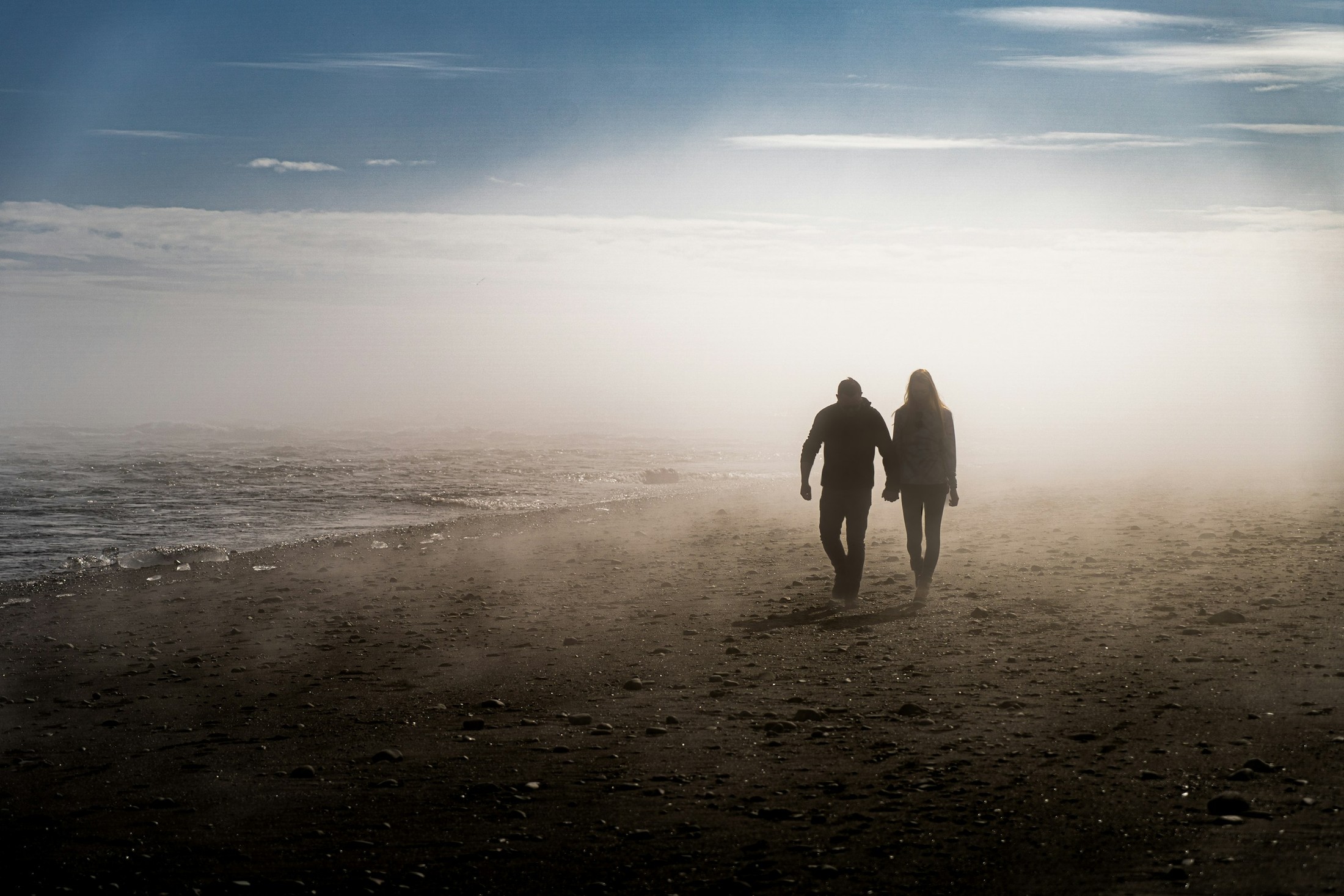 Love couple on Diamond Beach. Strip of black sand, located by Jökulsárlón glacier lagoon on the South Coast of Iceland. | Diamond Beach in Iceland